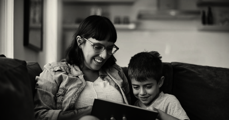 Frau und Junge an Tablet auf Sofa