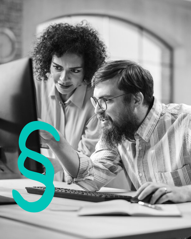 Eine Frau zeigt einem Mann etwas am Bildschirn